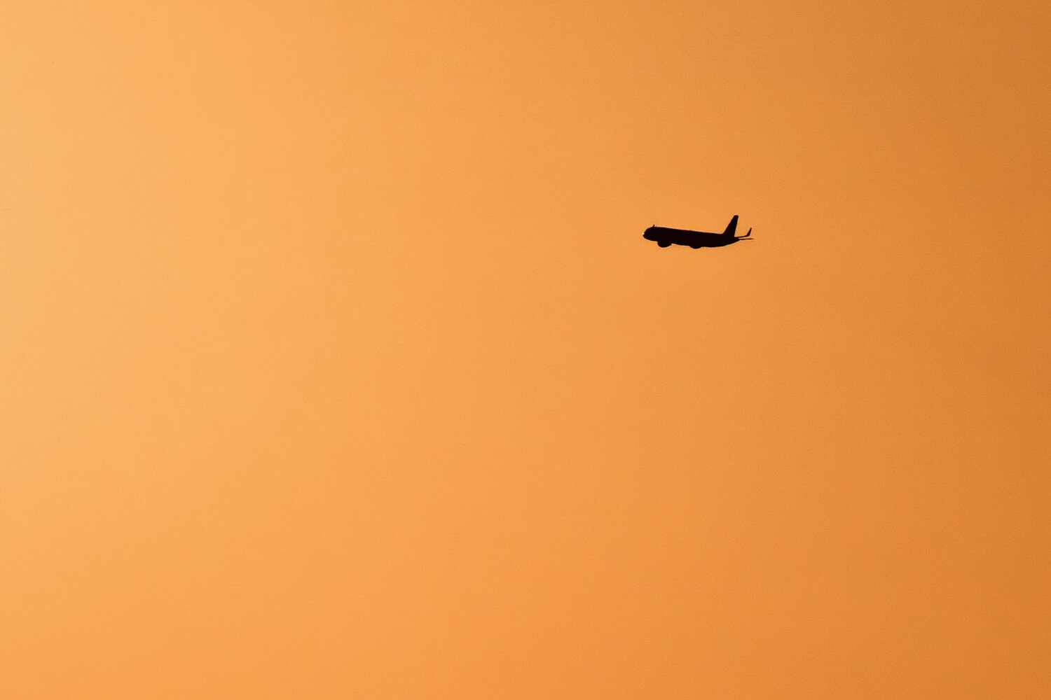 Minimal Airplane Against Solid Orange Sky