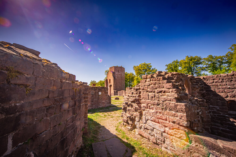 A detailed wide landscape photo showing ancient red sandstone ruins and stone tower of St Michael Monastery under bright sunny blue sky