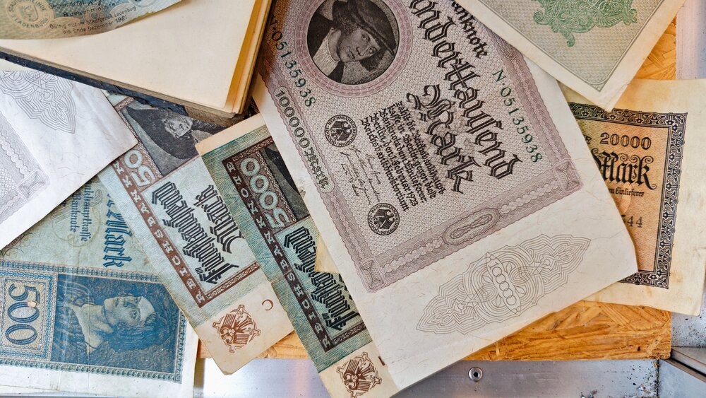 A detailed flat lay still life photography showing historical German Weimar Republic banknotes Reichsbank inflation marks paper currency collection