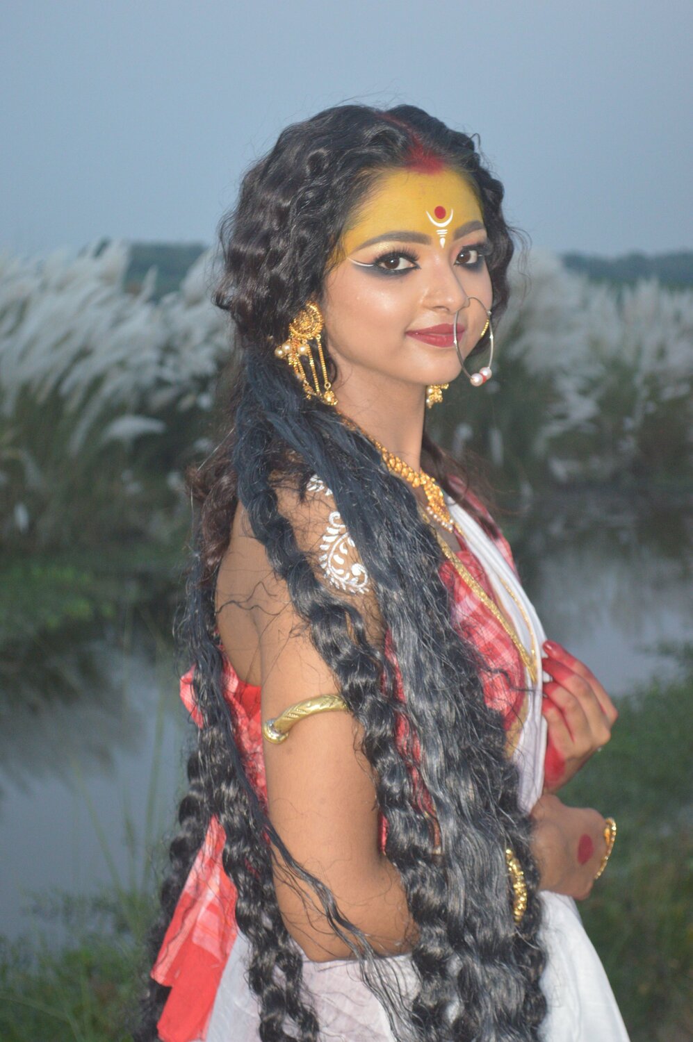West Bengal Festival Durga Puja A girl dressed as Durga stands next to a cashew tree.