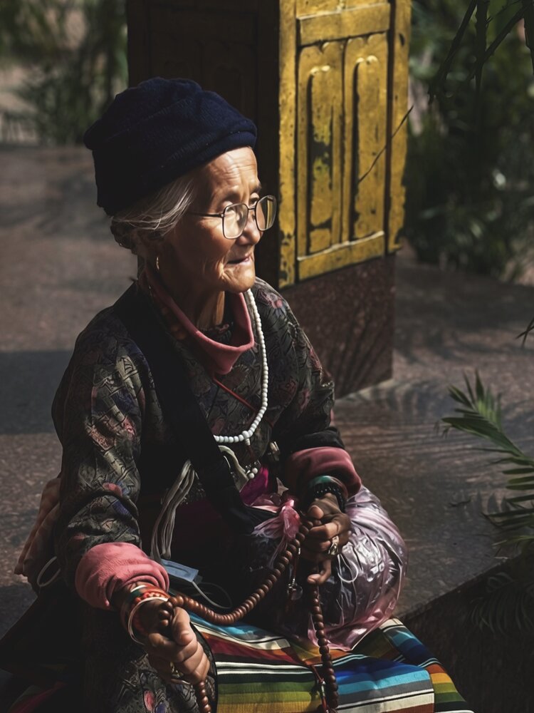 Elderly Tibetan Buddhist woman praying alone with mala beads in Nepal
