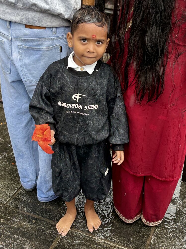 Young boy waiting in the rain at the India bus terminal in Pokhara, Nepal