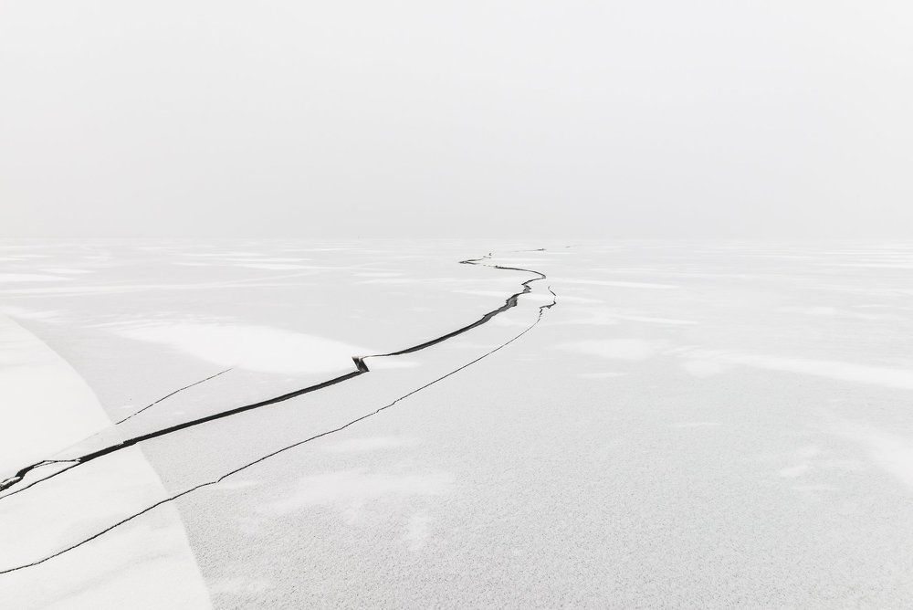 Crack in the ice on a frozen lake covered with snow.