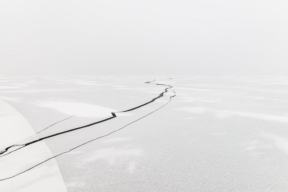 Crack in the ice on a frozen lake covered with snow.