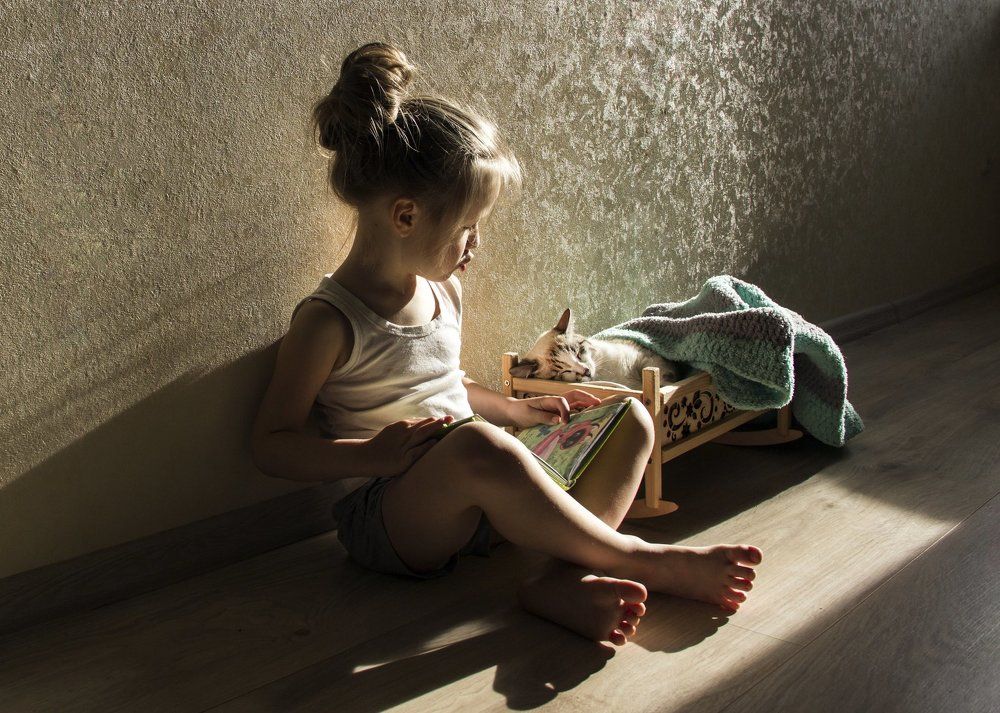 Девочка укладывает спать котенка