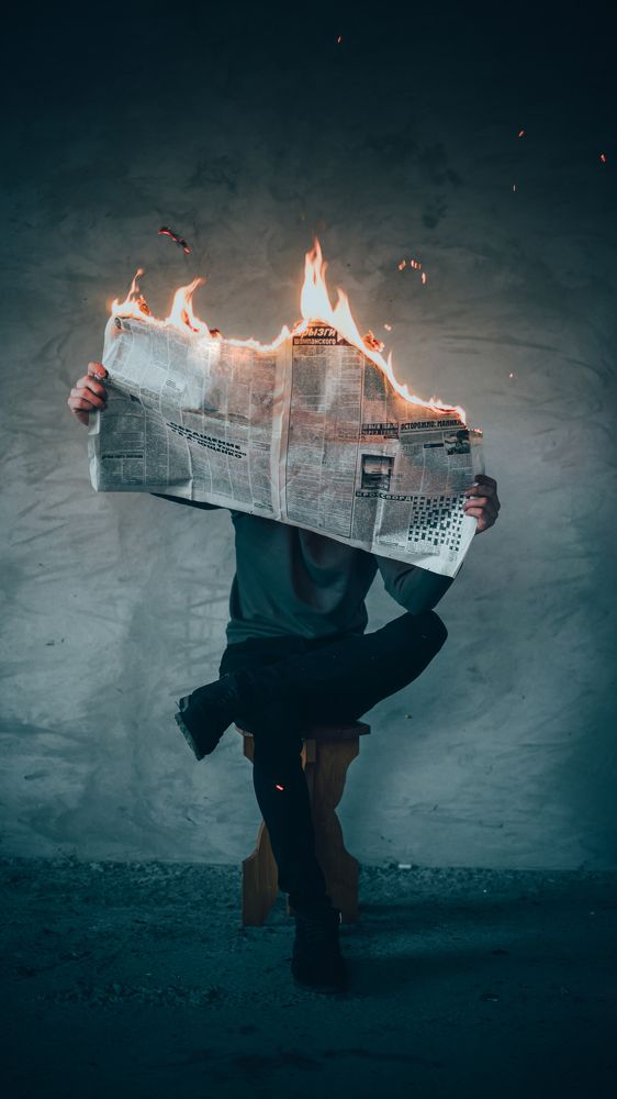 man reading burning newspaper
