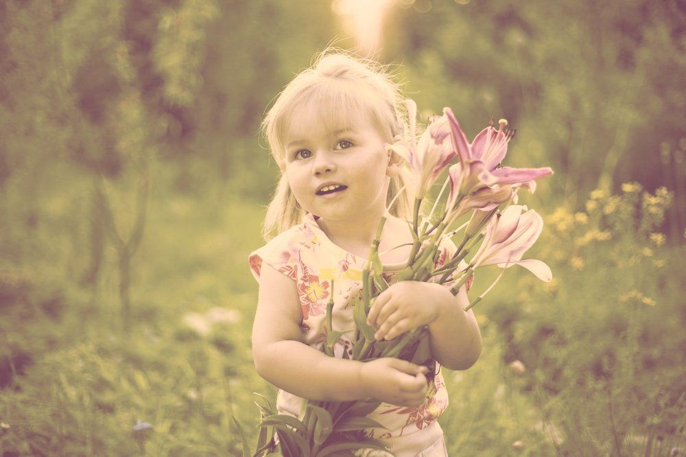 Beautiful white little girl with a smile and a bouquet of flowers