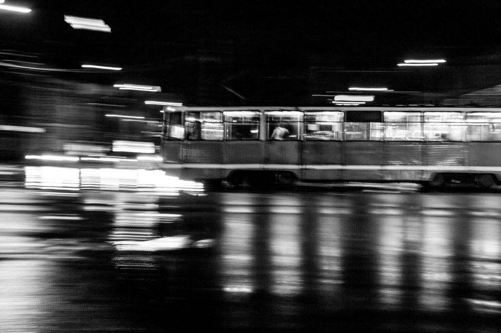 Tram rides through the night city in the rain