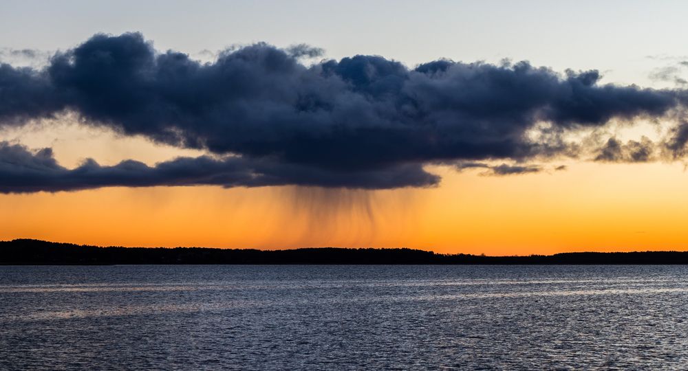 The bright sunrise with a black cloud above the lake
