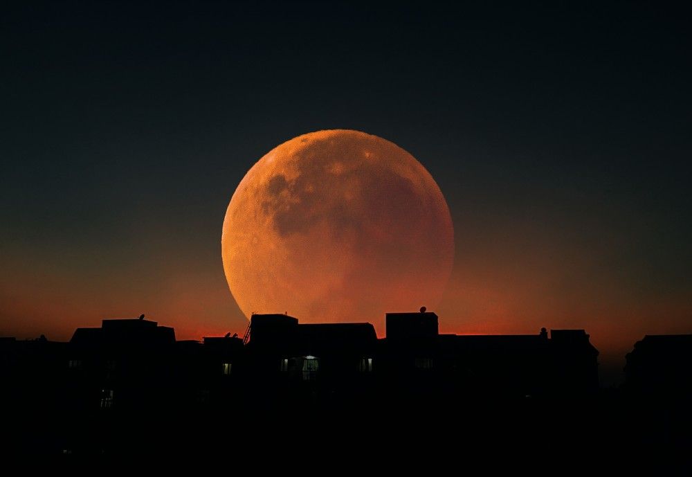 Red moon behind the building