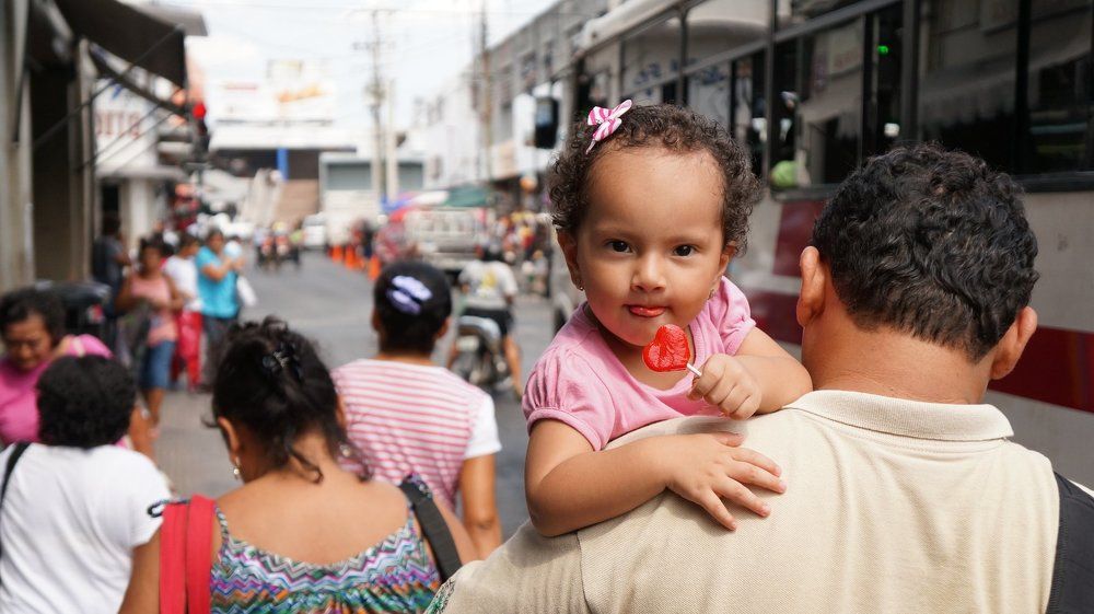 На отцовских руках и с конфетой.