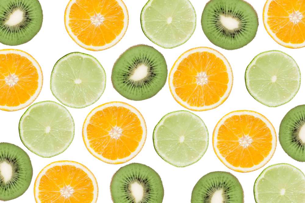 Colorful pattern of kiwi, lime and oranges. Top view of the citrus fruits and sliced kiwi. On white background.