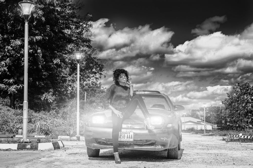 A lady sitting in front of a car