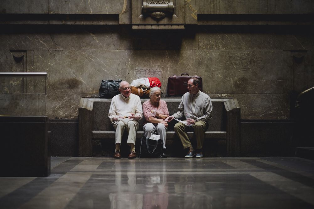 Three old people waiting on a bench