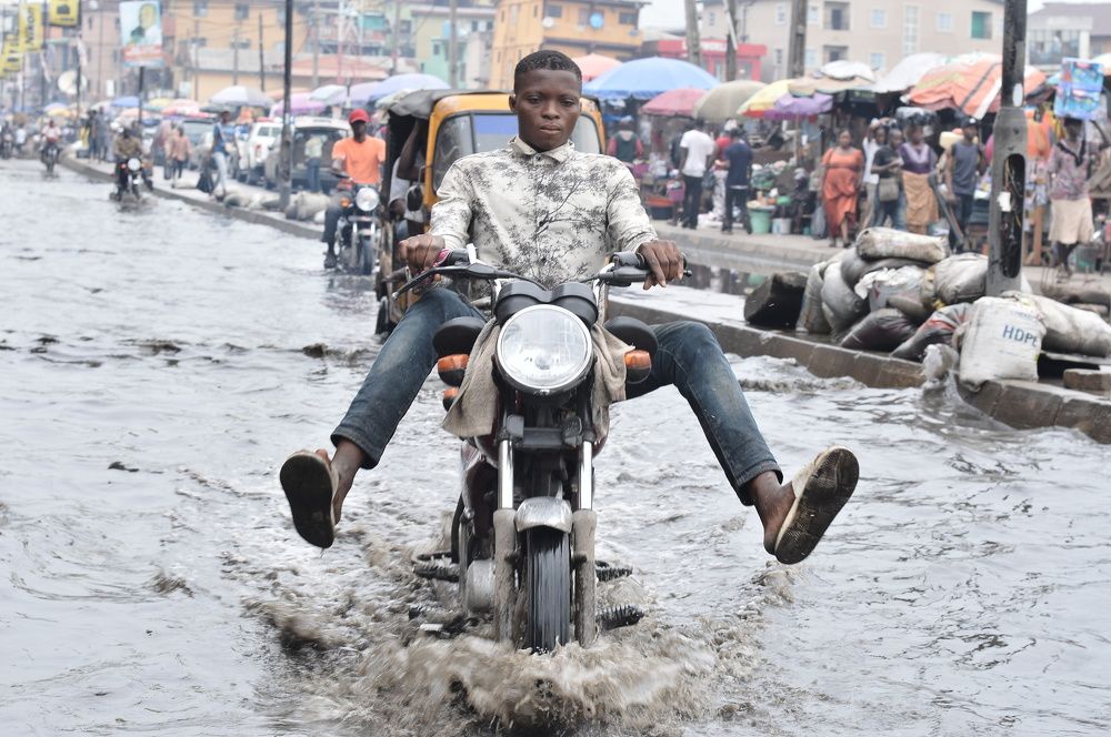 Wading through the odds: a motorcycle rider wade through a flooded portion of the ( lagos island)