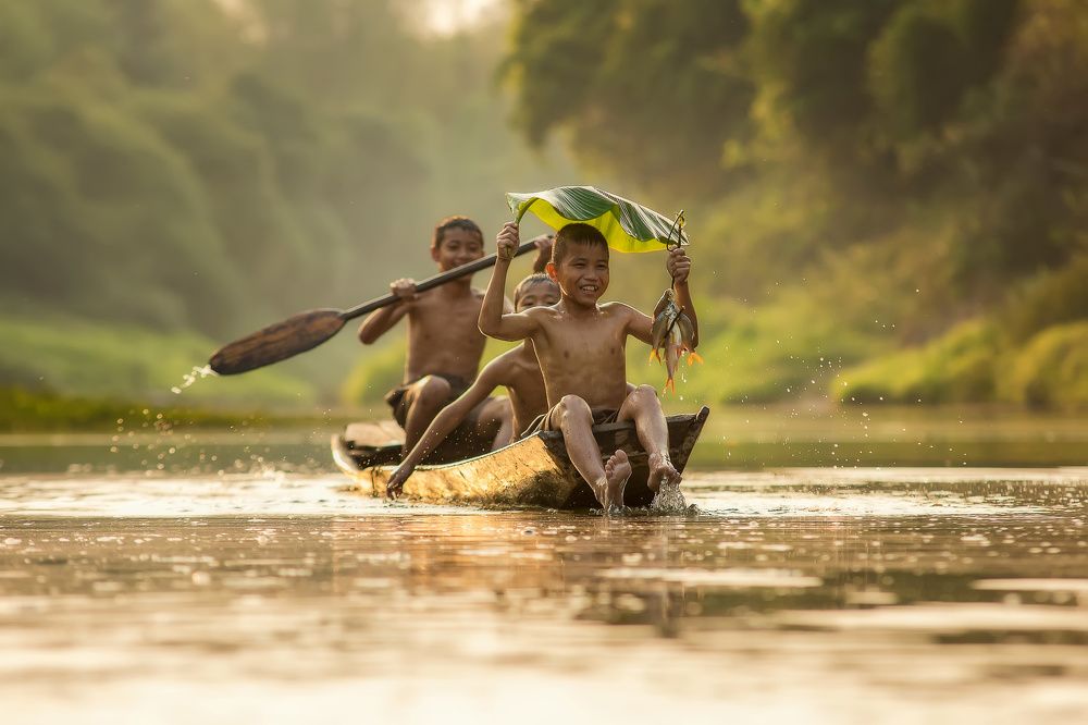 Asia children enjoying in boat on beautiful river.