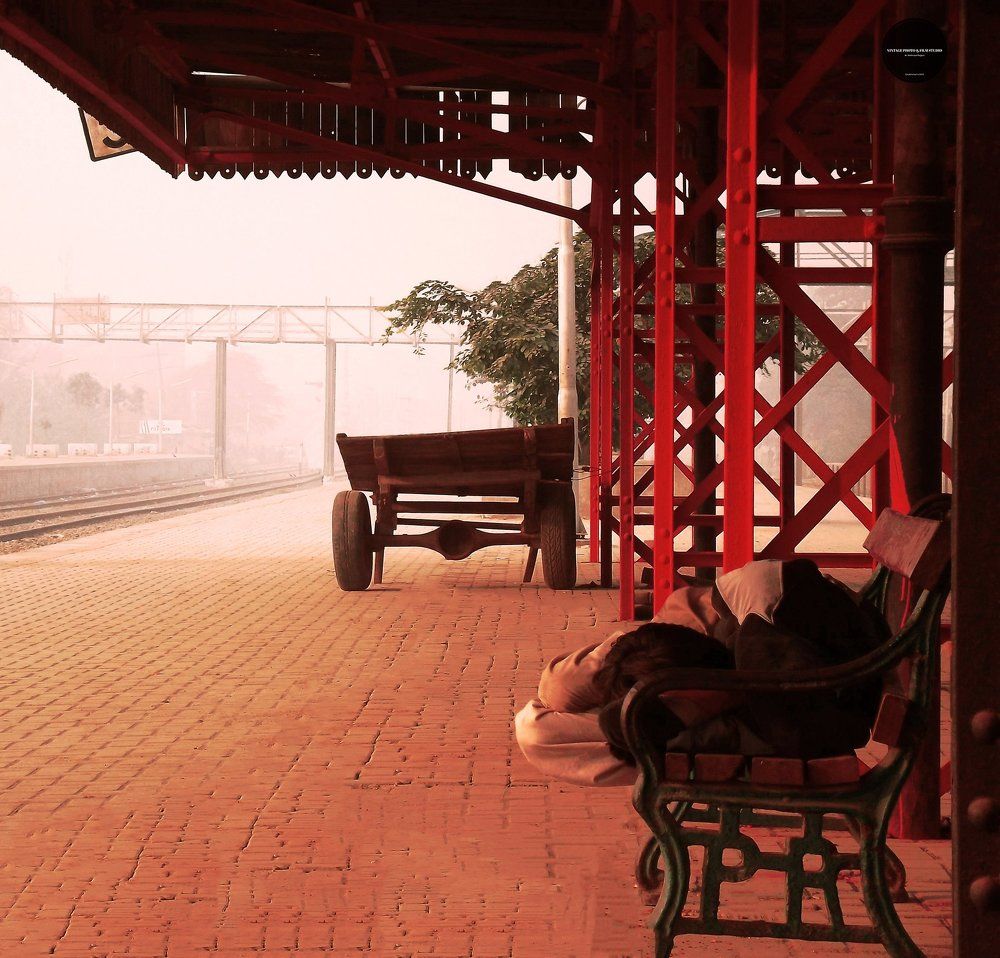 A Homeless begger laying on station bench