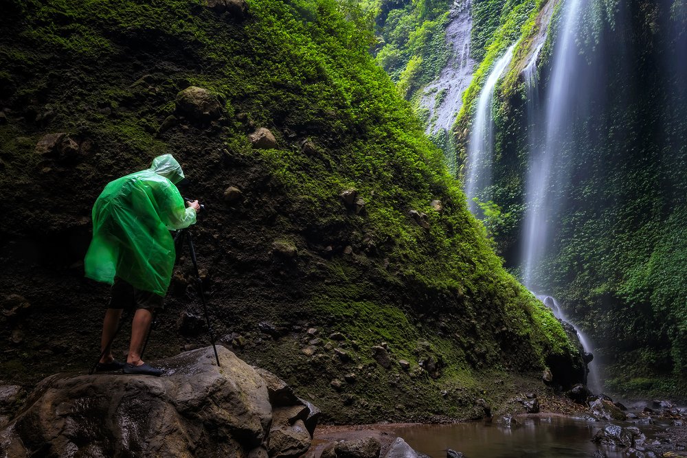 Man Standing In Front Of Waterfall.