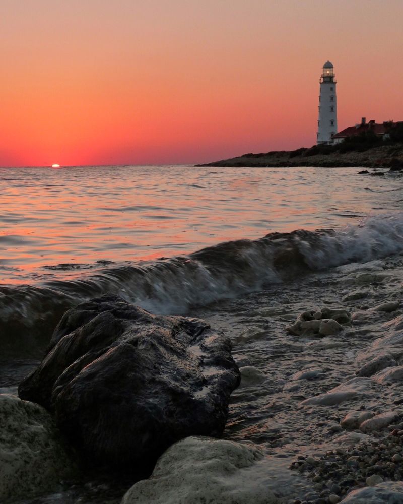 Первый огонёк маяка провожает последний луч заката