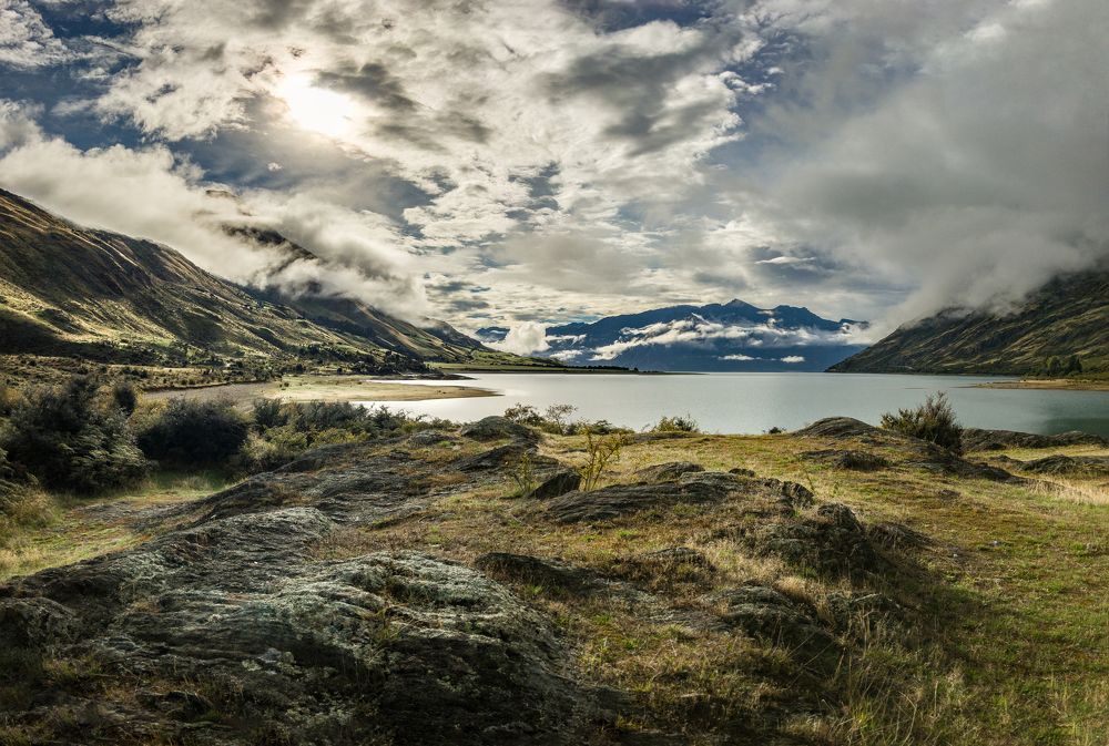 The sun shines over the mountains and through the clouds