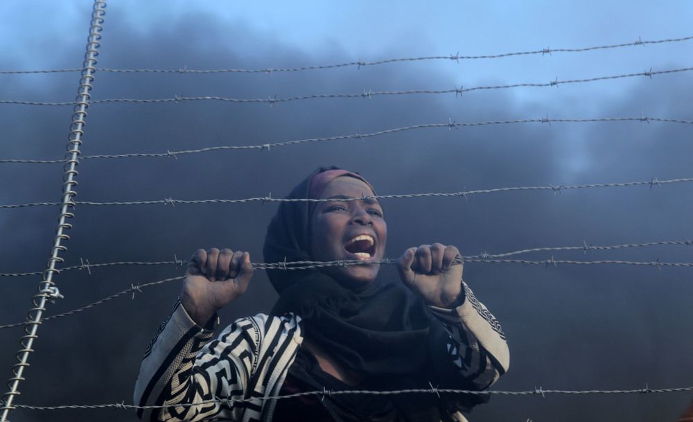 A Palestinian woman shouts slogans as other Palestinians burn tires in response to Israeli interventions during a "Great March of Return" demonstration on the Israel-Gaza border in Gaza City,