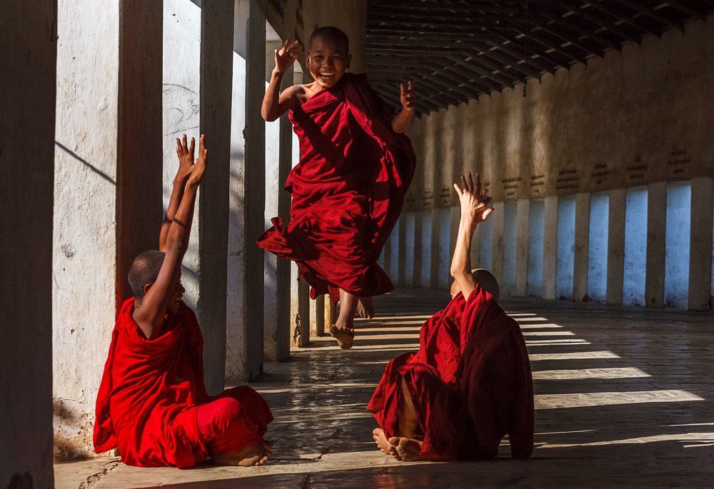 Юные монахи играют в галерее. Бирма.