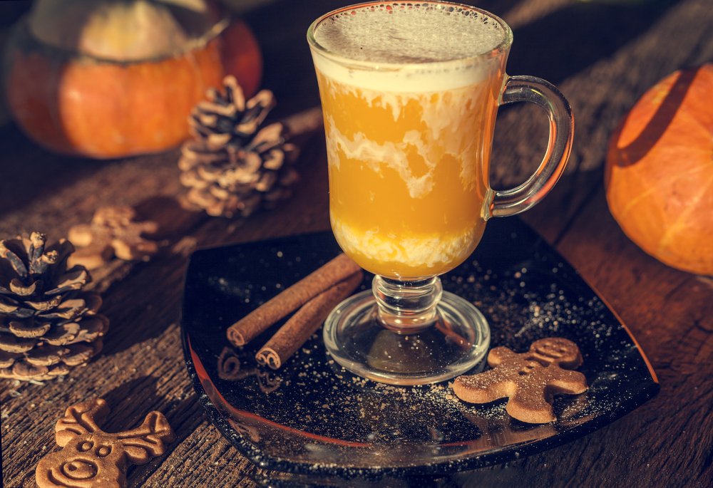 natural pumpkin juice, a composition of a glass of juice on a pumpkin background, on a wooden table in warm sunlight