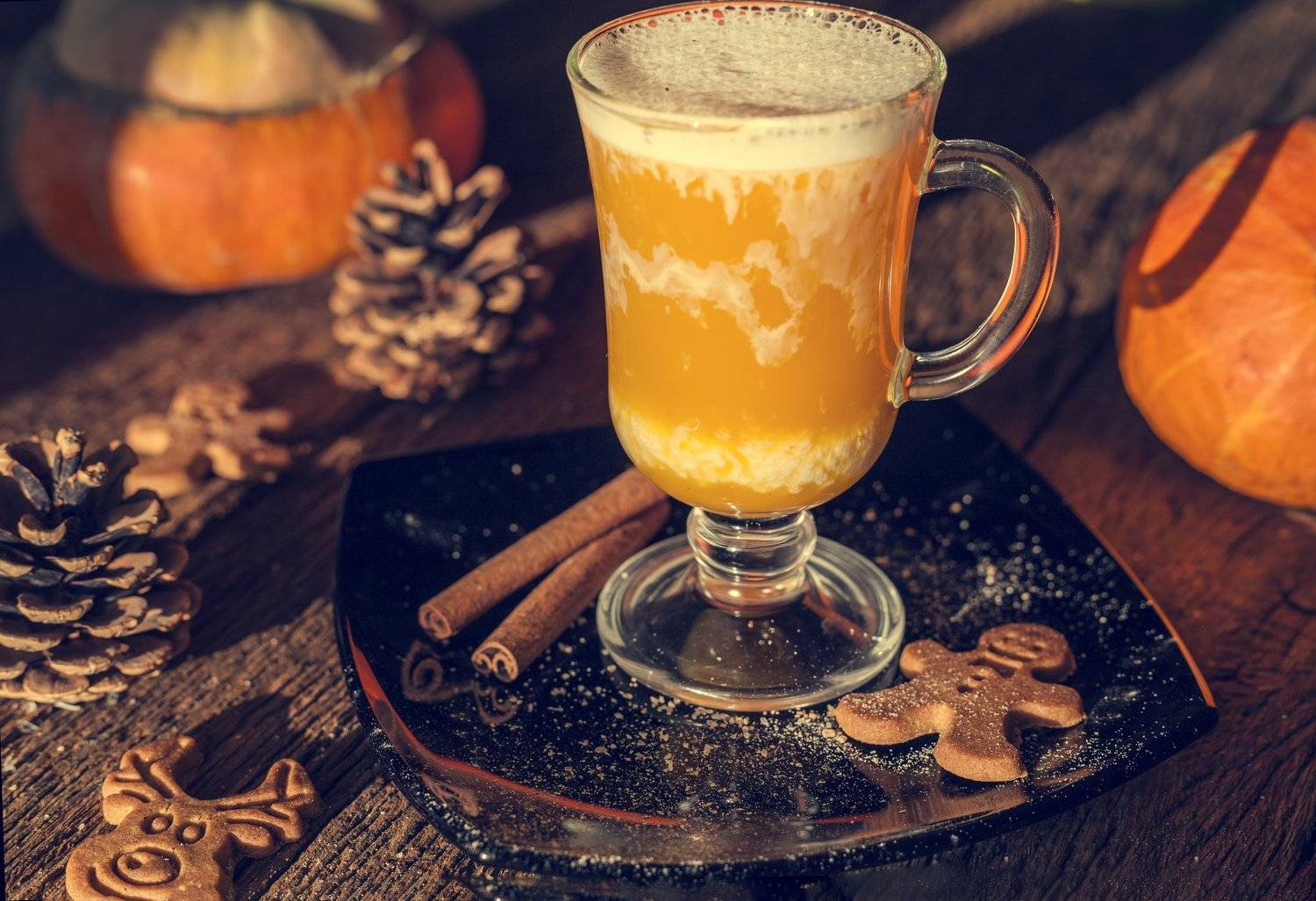 natural pumpkin juice, a composition of a glass of juice on a pumpkin background, on a wooden table in warm sunlight