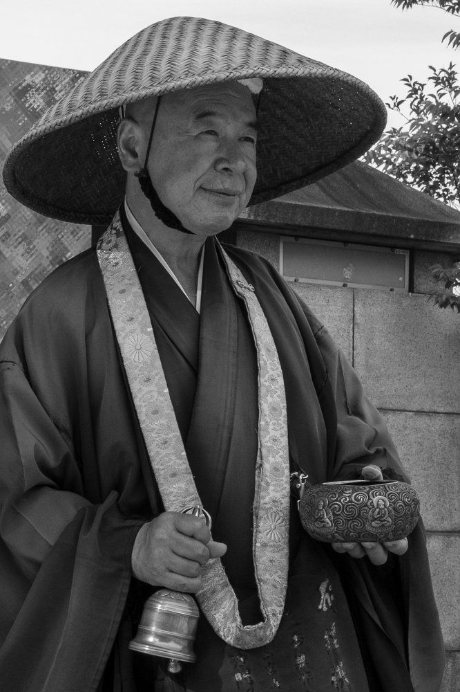 Монах, собирающий пожертвования,  на улице в  Токио.