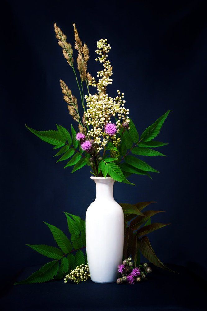 bouquet of summer flowers with Rowan leaves in a white vase
