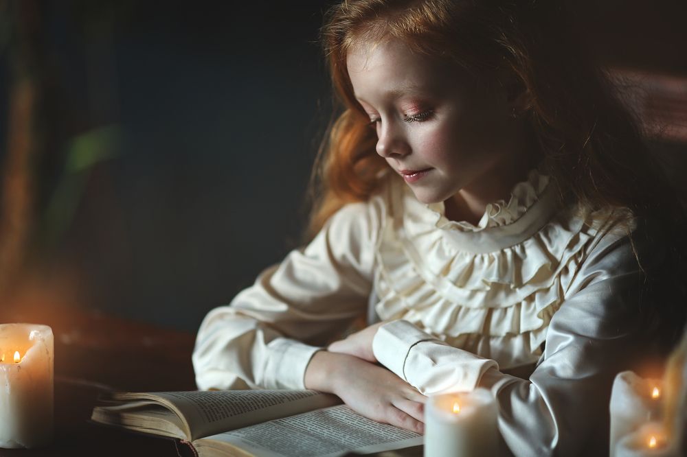 девочка читает книгу при свечах