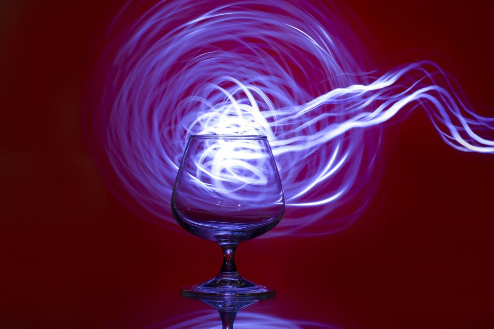 Glass still life "A glass on a red background with a drawing light"