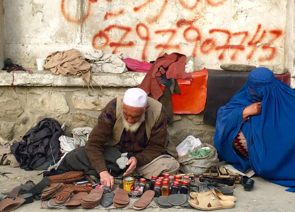 A poor Man who is sewing the old shoes