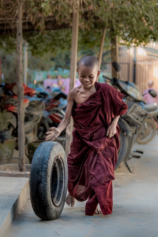 Бирманский монах играет с автомобильной шиной