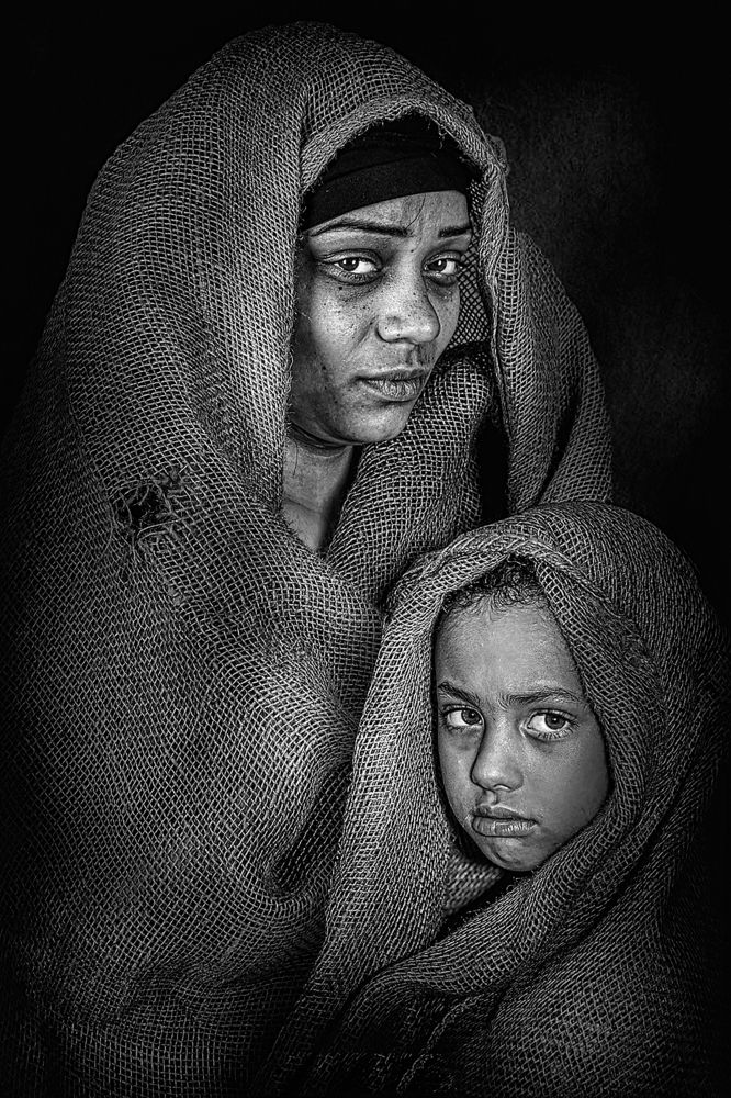 The mother\'s look is full of sadness and the girl\'s face is full of challenge