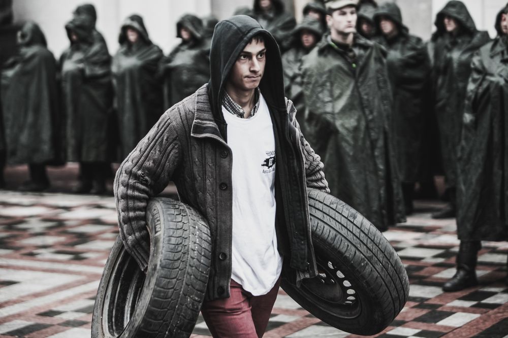 Протестующий несет шины под парламент Украины чтобы поджечь их в знак протеста.