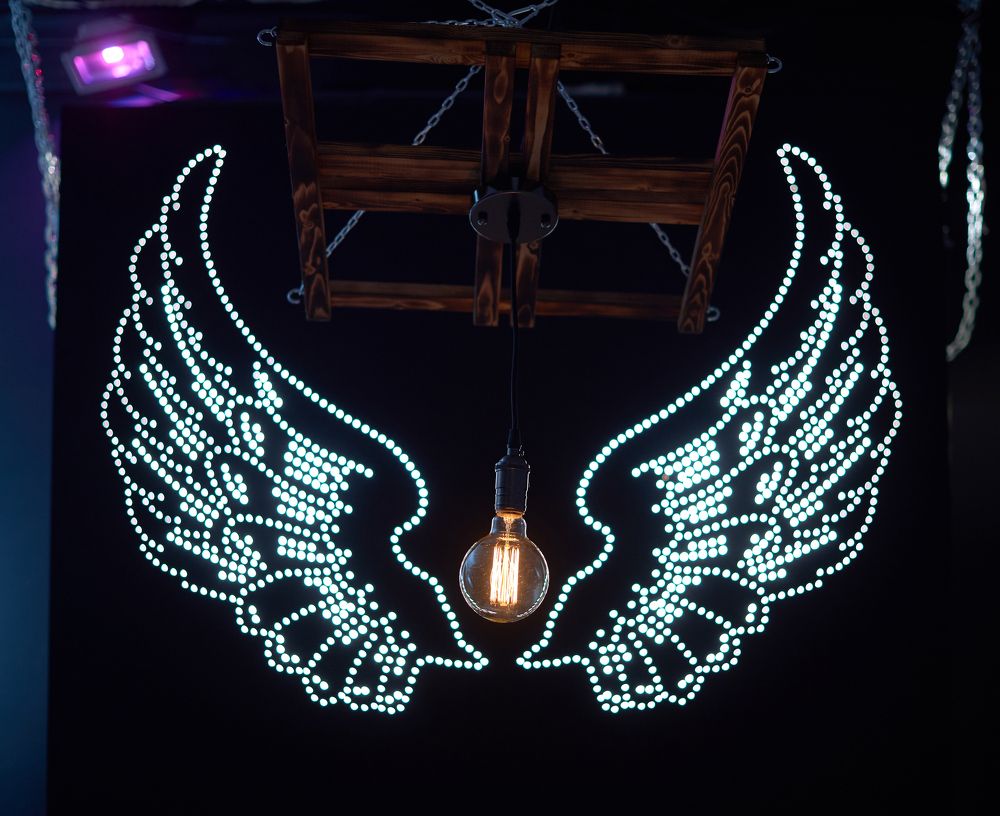 Лампа-люстра на фоне светового пано крылья