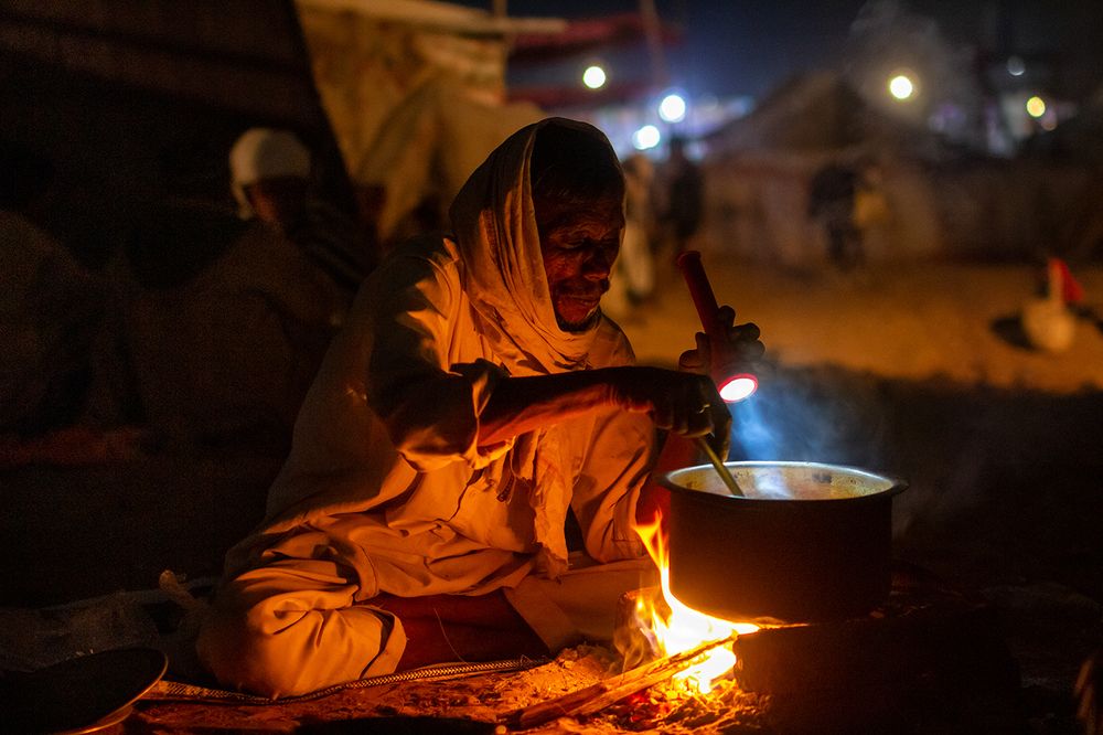 A camel shepherd is preparing food under the sky in Pushkar Fair