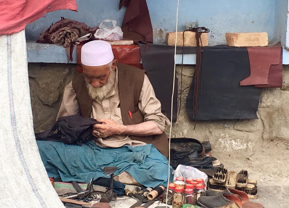 A poor Man who is sewing the old shoes