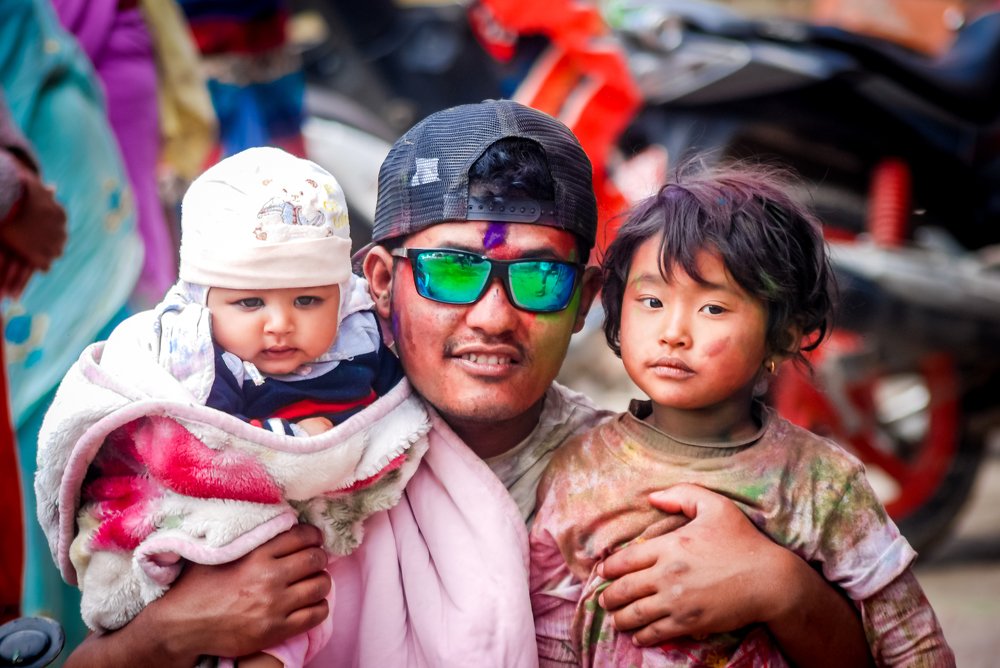 A father and his kids celebrating Holi festival