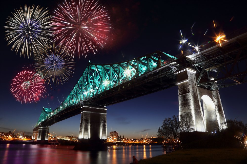 Colorful fireworks explode over bridge.