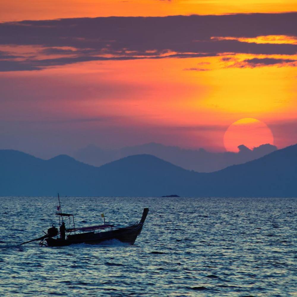 Longtail boat is sailing at sunset