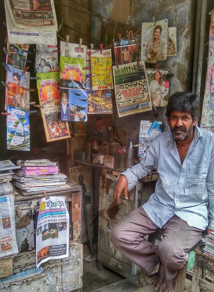 Shabbily dressed man selling newspapers