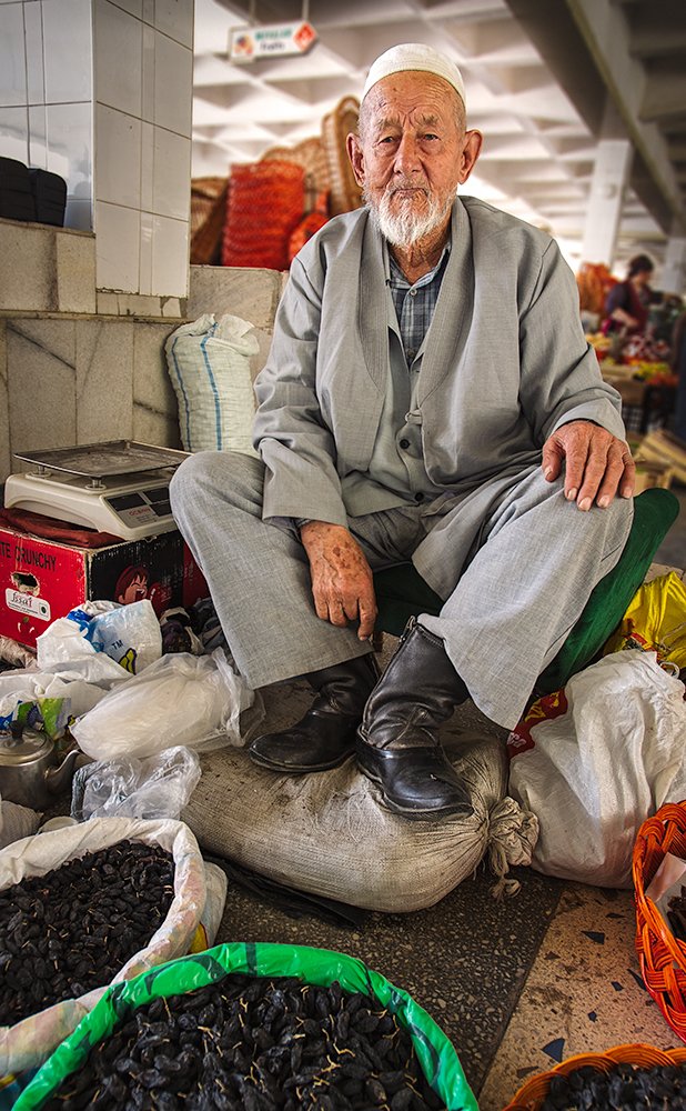 Пожилой торговец сухим виноградом на самаркандском рынке.
