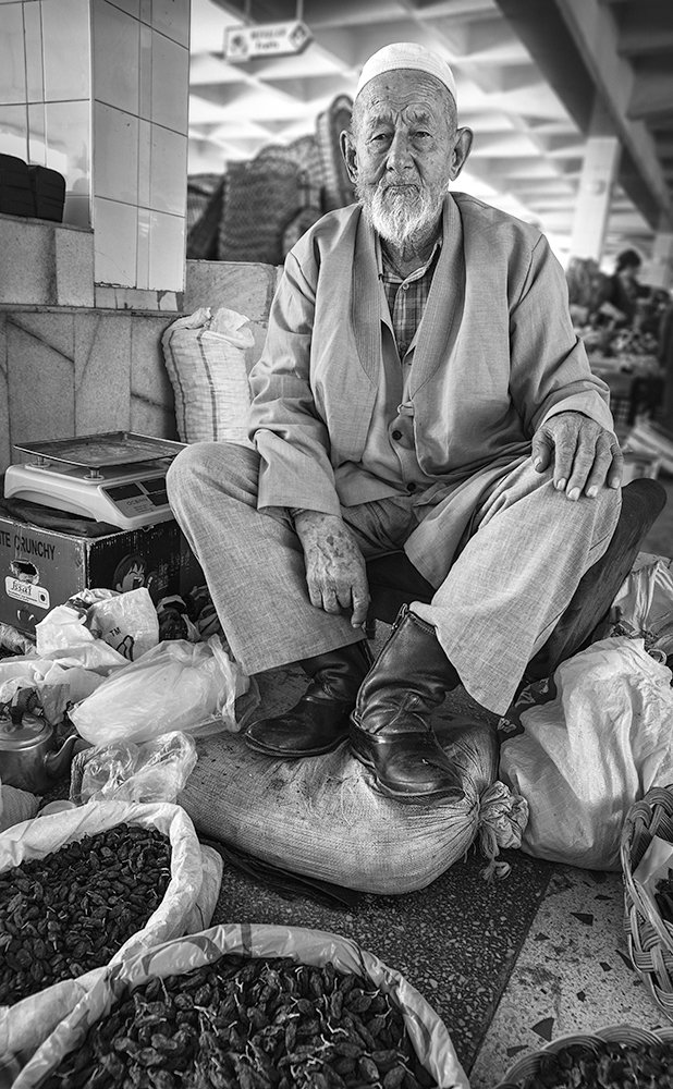 Пожилой торговец сухим виноградом на самаркандском рынке.