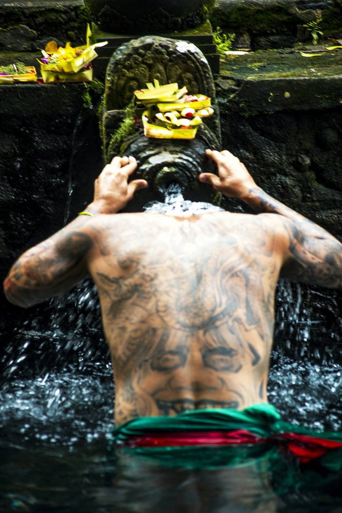 Tattoo man bathing on the Holy Waters of Tirta Empul Temple, Bali, Indonesia.