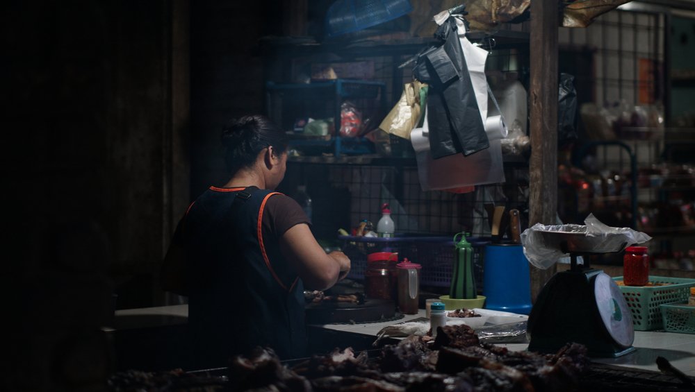 Woman cooking wild pork in a Malaysian market