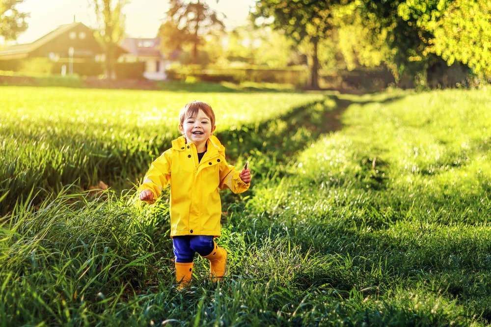 Happy boy in yellow raincoat running