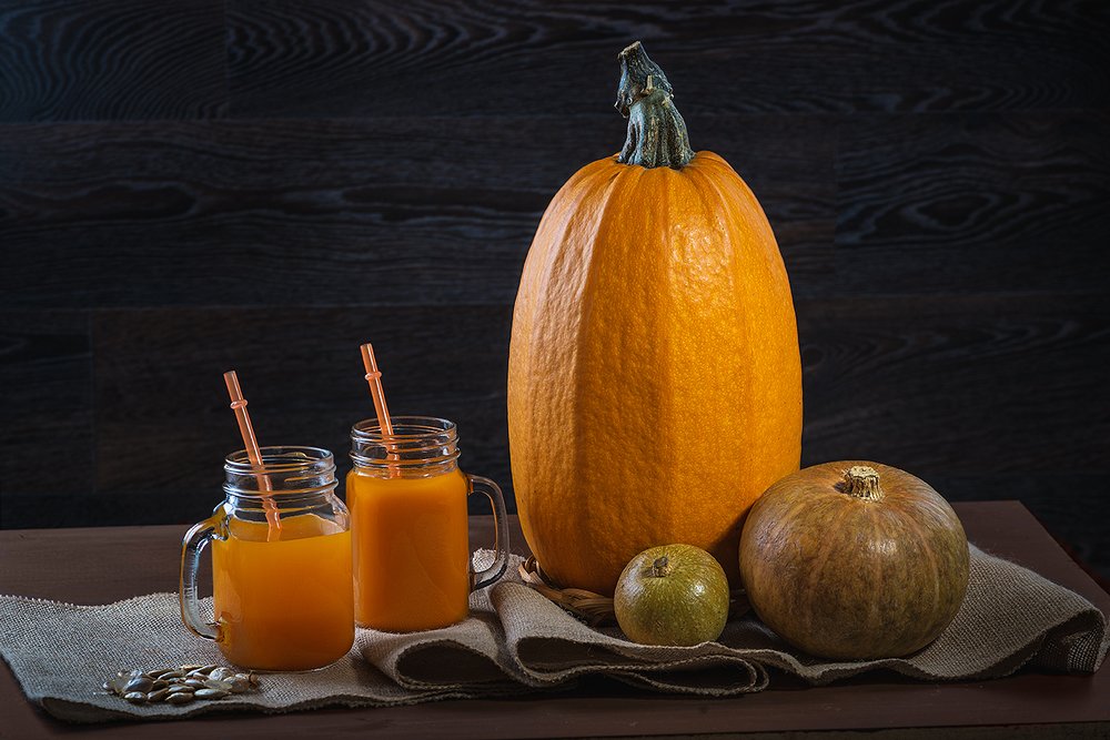 Fresh pumpkin juice and pumpkin on a burlap on a wooden table.