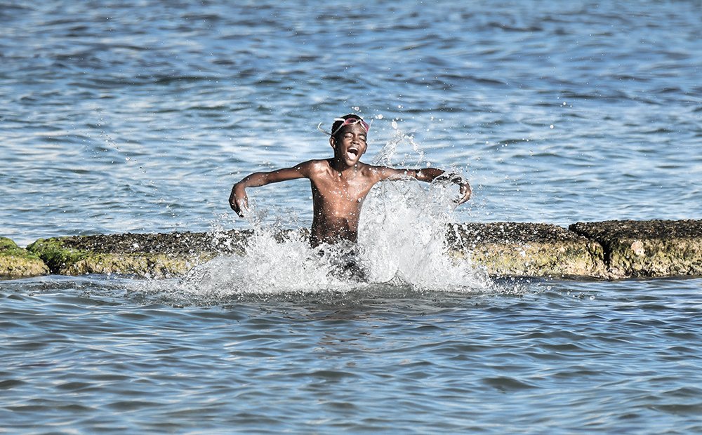 Dominican Boy playing jump and splash water.